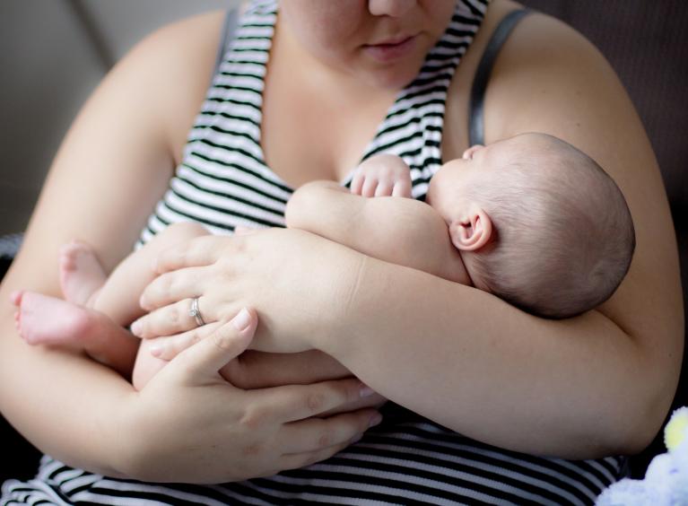 A mother holds a young baby in her arms