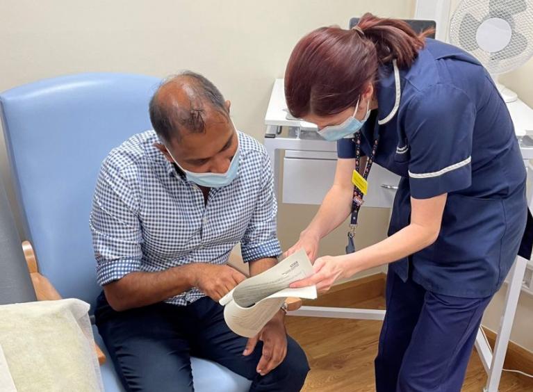 A research nurse guides a patient through a document