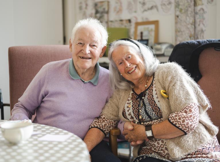 An older couple smile and look at the camera together