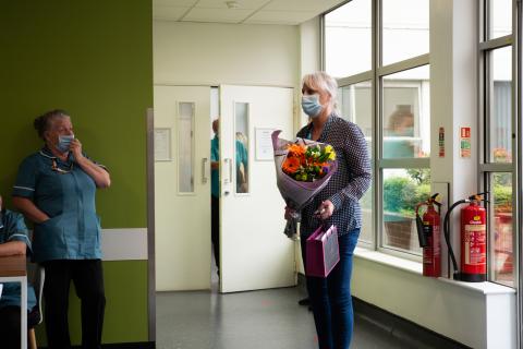 A person arrives to the hospital with a bunch of flowers.