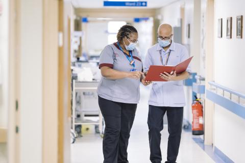 A student nurse looks at notes with a colleague