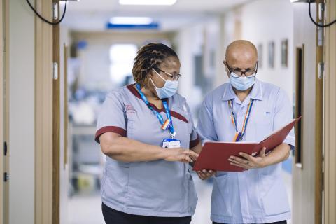 Two nurses look at notes together.