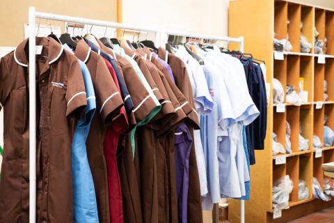 A selection of nursing and care staff uniforms hanging on a clothes rail 