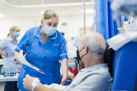 A nurse speaks to a patient who is seated