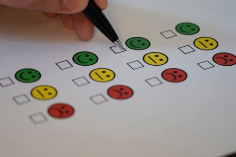 A person completing a feedback survey, about to tick below an image of a green smiling face