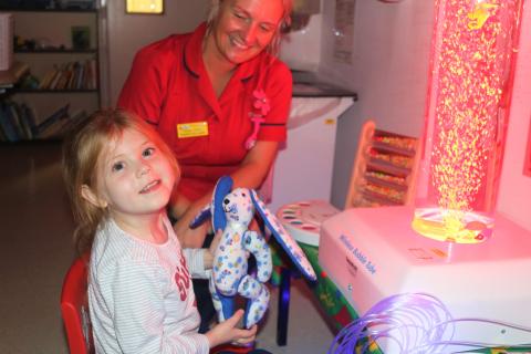 Hospital staff passes a stuffed toy to a young patient