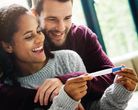 A couple look at a pregnancy test with delight