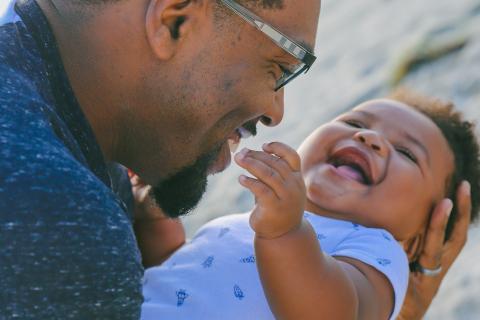 A happy father holds his laughing baby