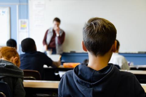 Child sat in class room facing teacher