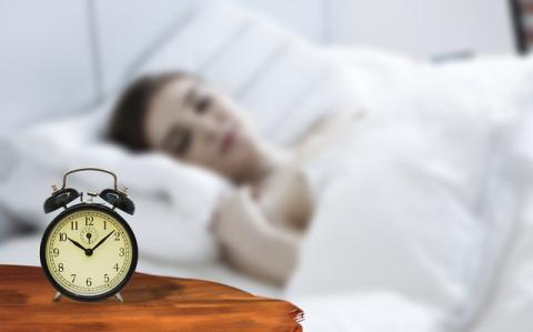 alarm clock with a blured image of girl sleeping in background.