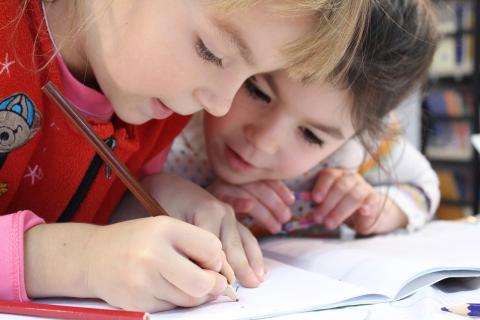 Two children writing in their book