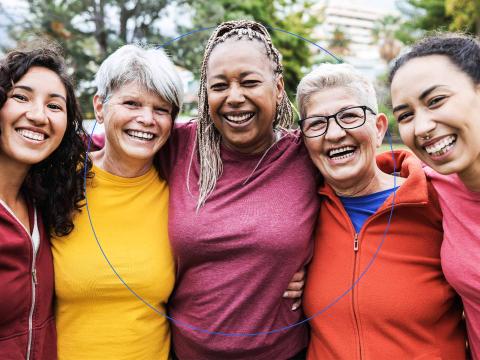 Five women standing shoulder to shoulder, smiling at the viewer