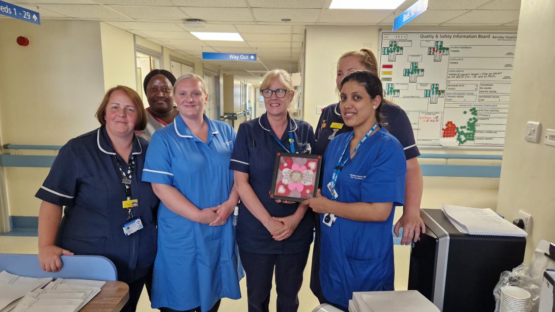 The AMU team receive their framed hearts